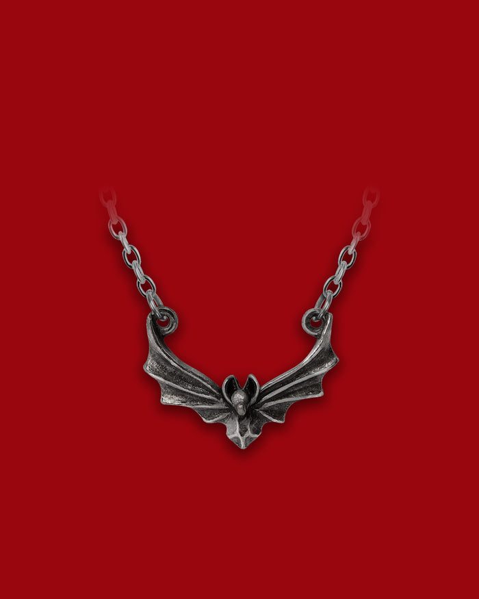A stylised flying bat pendant crafted in antiqued English pewter, suspended from a delicate chain, this gothic piece evokes nocturnal wings beating through silent eaves and adds dark romantic flair to any neckline.