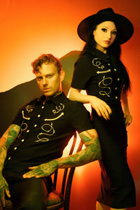 This black Bengaline men’s shirt combines edgy western inspiration with refined gothic style. Featuring intricate barbed wire and arrow embroidery across the chest, the fitted short-sleeve design contours the body while offering flexibility and comfort. The matte snap buttons add a subtle industrial touch, giving the piece a weathered, masculine appeal that makes it ideal for both casual and statement styling.