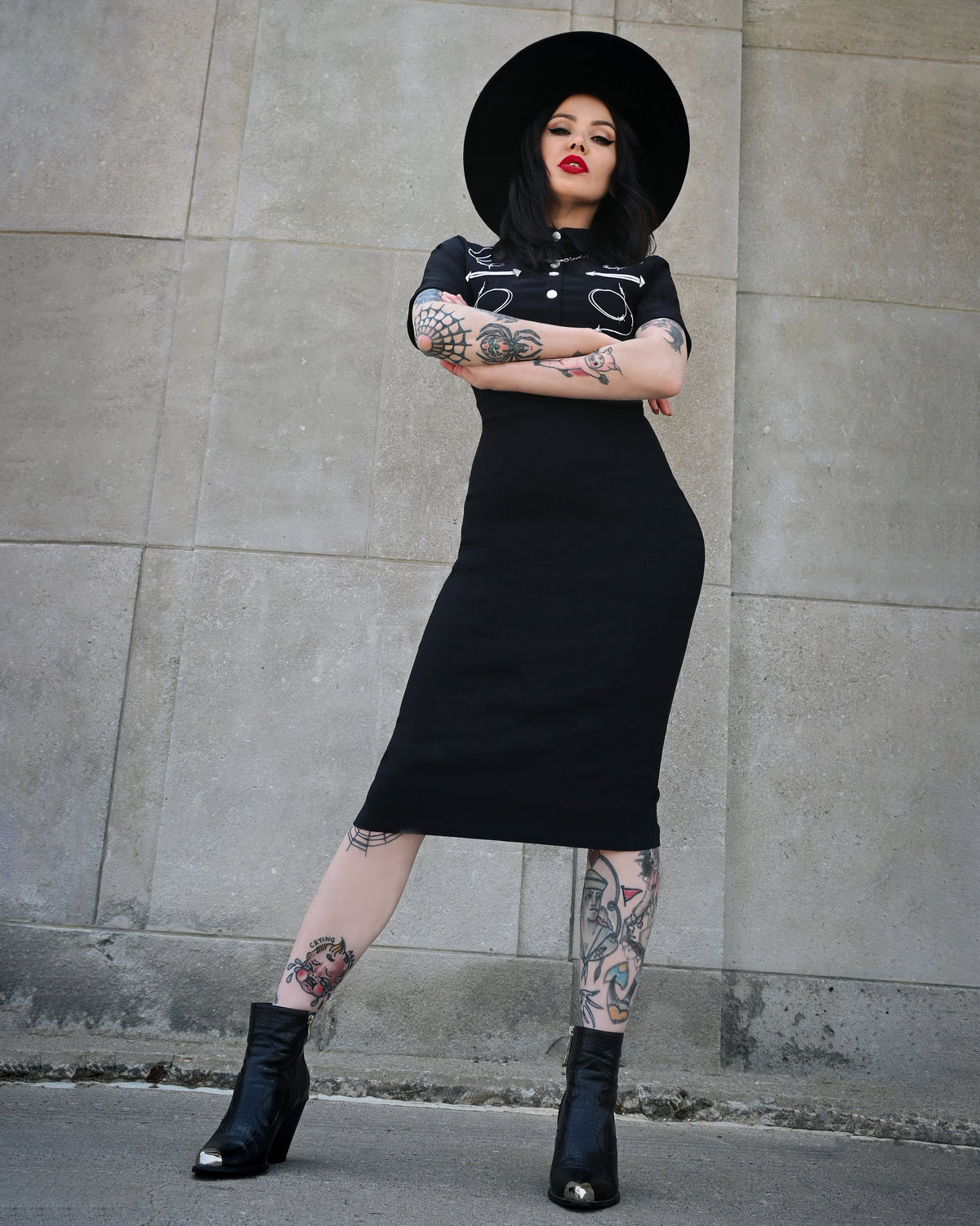 Designed for bold elegance, the black Barbara Dress hugs the figure with a perfect balance of stretch and support, thanks to its high-quality Bengaline construction. The piece is adorned with distinctive barbed wire embroidery, adding a rebellious twist to the classic western aesthetic. Refined piped yokes shape the shoulders and bust, while decorative snaps on the front and a hidden zipper in the back complete the sophisticated yet daring silhouette.