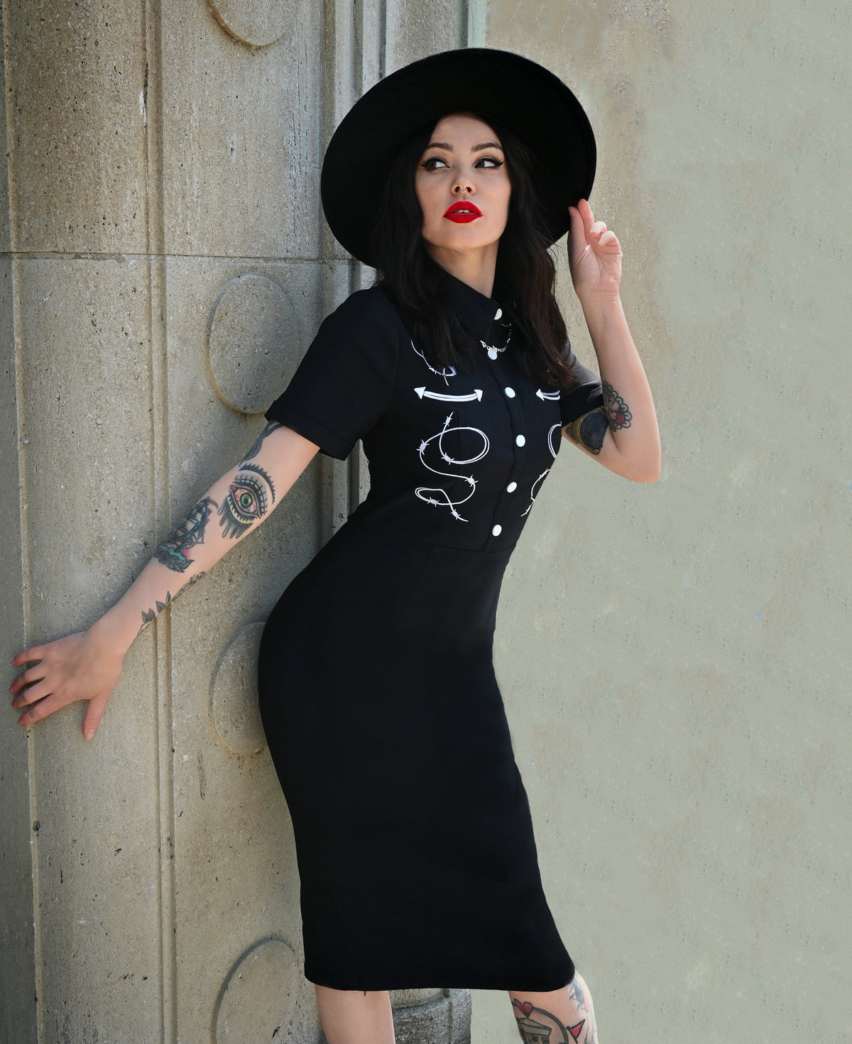 The black Barbara Dress embodies modern western allure with its form-fitting Bengaline fabric and striking embroidered barbed wire motif. Its tailored design includes carefully piped yoke detailing for contour and style, complemented by a row of front snap buttons that enhance its vintage charm. Finished with a concealed zipper in the back, this curve-hugging dress delivers both comfort and structure—ideal for statement looks that merge classic femininity with a bold, barbed-edge aesthetic.