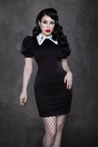 The Bellatrix Dress showcases a sleek, figure-hugging black suede body with dramatic puff sleeves and an exaggerated oversized white collar adorned with black sword embroidery, delivering a striking vintage gothic aesthetic that blends retro 60s style with contemporary alternative fashion trends, ideal for bold, statement outfits.