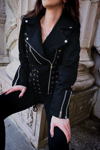 Black Vixxsin Chantira Jacket made from 100% cotton with polyester lining, designed with a fitted biker silhouette, prominent grommet lace-up accents across the jacket, asymmetrical front zipper, zipped sleeve cuffs, and adjustable side ties, combining comfort with a strong, rebellious, and statement-making style.