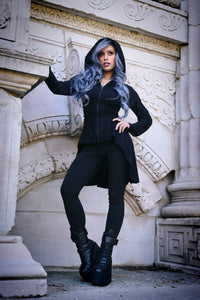 A black lightweight zip-up hoodie from Heartless made from 100% soft polyester, featuring a high-low hem, corset-style side lacing, and adjustable back ties for a customizable fit, perfect for layering year-round with a fitted silhouette and oversized hood for an edgy style.