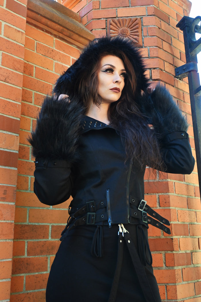 Heartless Effia Jacket in black with structured cotton blend outer, soft polyester lining, matte black spike studs, faux fur trim on hood and cuffs, asymmetrical zip closure, panel seaming, and adjustable side straps for a tailored, edgy cold-weather outerwear look.
