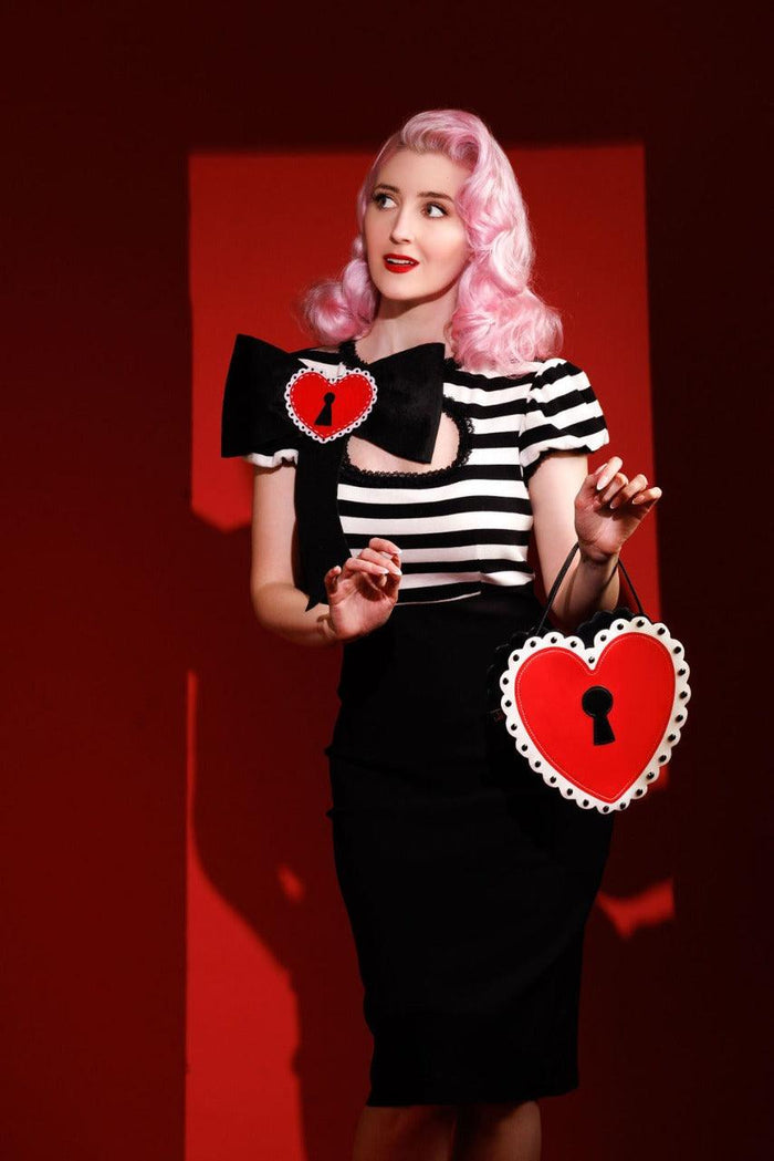 A Heart Locket Purse featuring a matte red heart with a black matte keyhole center, surrounded by a white scallop border and accented with black jewel studs, inspired by vintage valentine cards and perfect for adding a romantic, statement-making touch to any outfit.