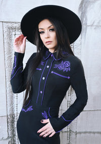 Stretchy bengaline June Dress in deep black and purple tones, highlighting long sleeves with subtle piped details, faux snap cuffs, fixed snap front closure, and ornate rose and thorn embroidery on key areas including collar, bust, hips, and cuffs, enhanced by crisp white piping for a standout spring dress.