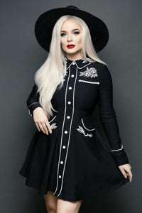 Black and white June Dress featuring a playful skater skirt and long piped sleeves with faux snap cuffs, decorated with intricate rose and thorn embroidery on the collar, cuffs, bust, and hips, accented with crisp white piping and deep functional pockets, combining feminine elegance with practical style for everyday wear or special occasions.