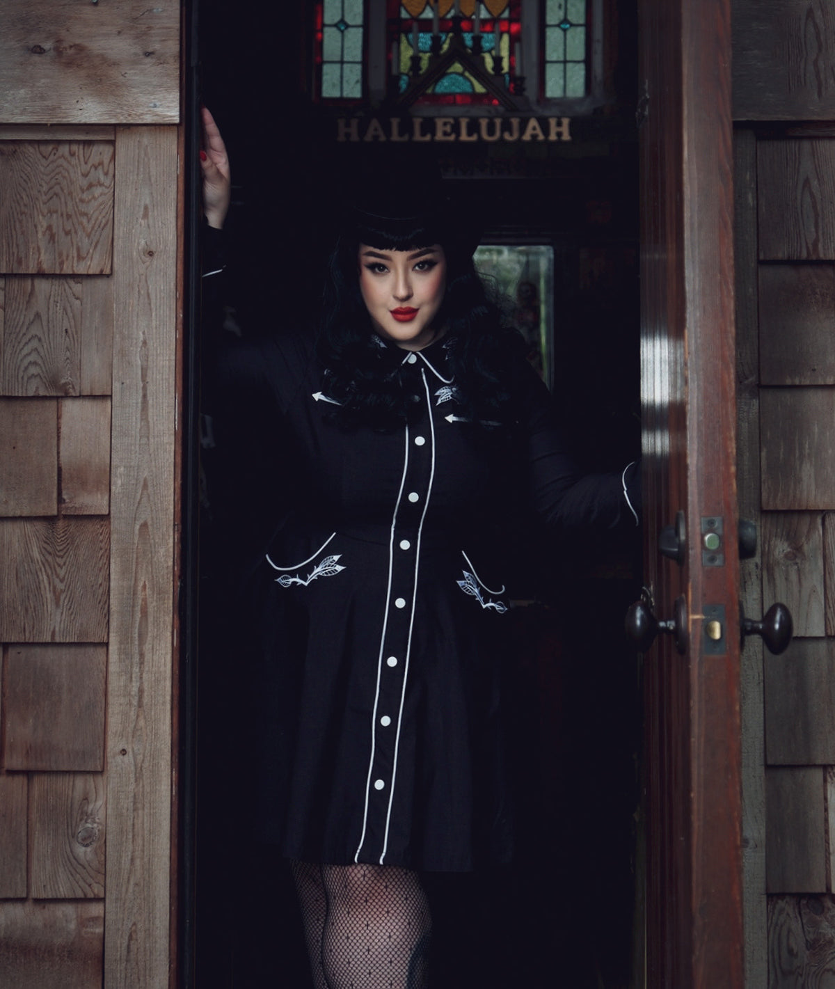 Elegant women’s skater dress in black with white piping, showcasing detailed rose and thorn embroidery across the collar, bust, cuffs, and hips, long piped sleeves with faux snap cuffs for a polished finish, a flattering A-line skater skirt, and deep pockets, perfect for casual outings, brunch dates, or versatile office styling.