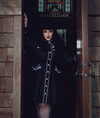 Elegant women’s skater dress in black with white piping, showcasing detailed rose and thorn embroidery across the collar, bust, cuffs, and hips, long piped sleeves with faux snap cuffs for a polished finish, a flattering A-line skater skirt, and deep pockets, perfect for casual outings, brunch dates, or versatile office styling.