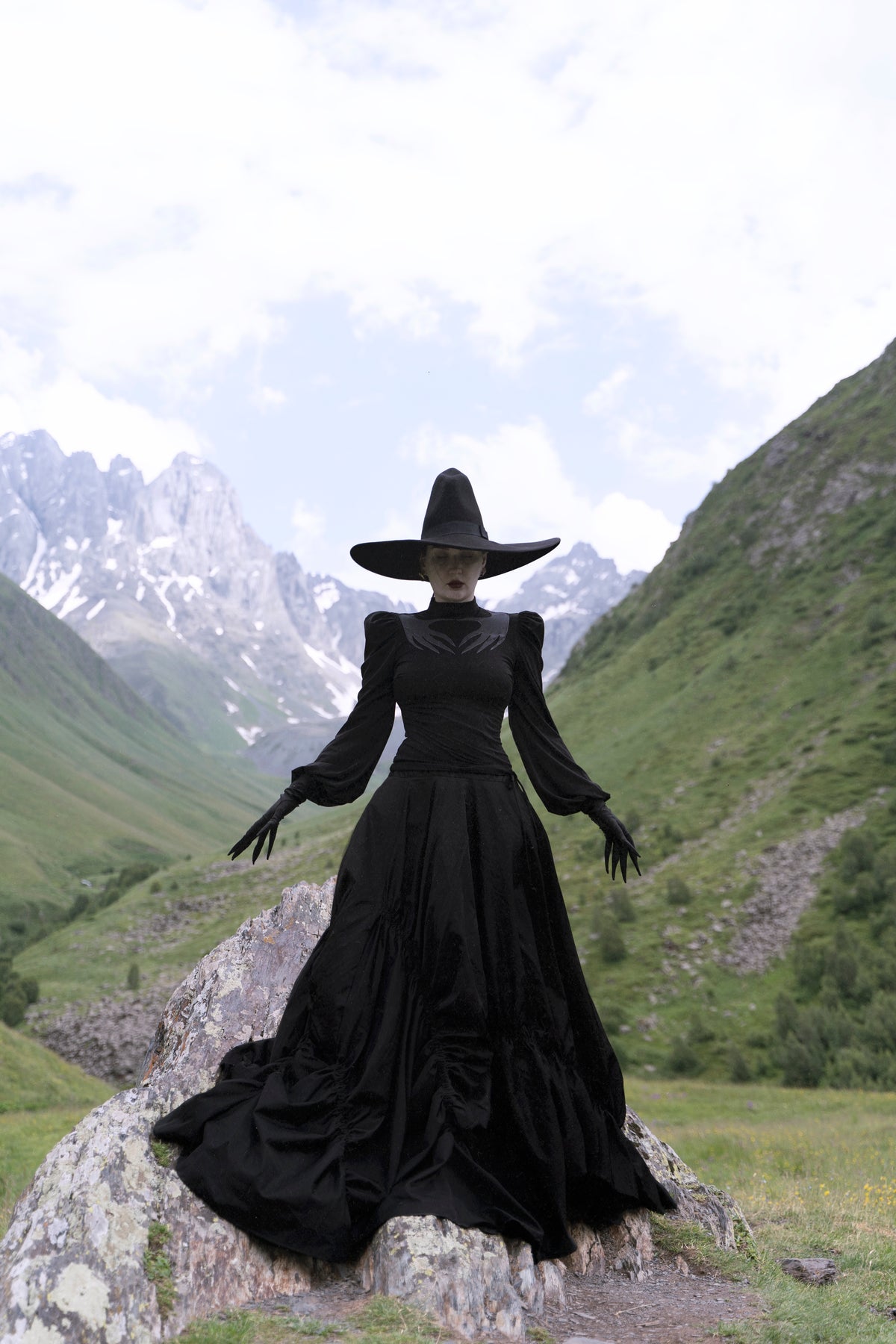 High-stretch polyester black Phantom Blouse with a sheer mesh cut-out across the chest displaying Naya’s haunting hand design, structured puff shoulders, and long gathered sleeves, offering a dramatic silhouette ideal for layering or standalone wear.