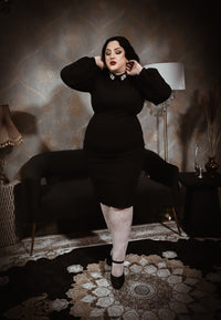 A fitted black dress with long puff sleeves and a high neckline, featuring a jeweled collar detail that adds a touch of elegance. The dress has a sleek, classic silhouette that flatters the figure, perfect for a polished and timeless look.