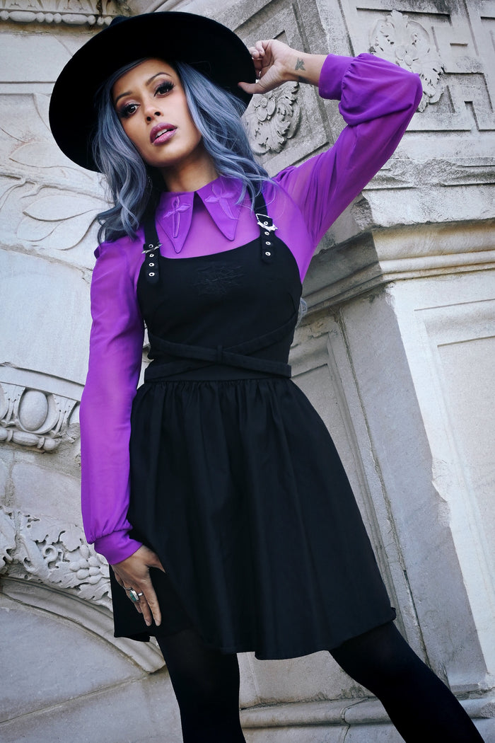 Elegant and modern, this black Bengaline skater dress showcases bold cross-front straps over the shoulders, a fitted bodice that transitions smoothly into a flowing A-line skirt, delicate front-panel embroidery nearly hidden for a refined surprise, and signature web-bing buckles that punctuate the waist for a fashion-forward structured look.