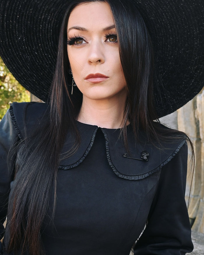 Matte black safety pin brooch featuring a sculpted skull detail at one end. Measuring 2 inches, this gothic-inspired accessory adds edgy elegance to collars, lapels, or bags—perfect for layering or wearing solo as a bold statement piece.