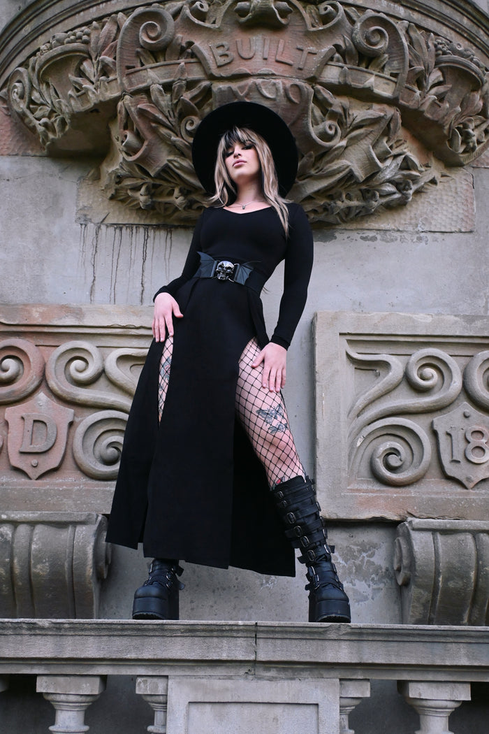 Wide gothic skull belt with shiny black skull centerpiece and faux leather bat wing detailing, designed with a stretchy elastic band for a snug, comfortable fit, and secure snap closure; ideal for adding bold, alternative flair to dresses, coats, tunics, or casual gothic wardrobe ensembles.