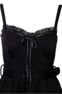 Classic fit-and-flare Love Bites Swing Dress in luxurious black poly blend, featuring a sweetheart bustline enhanced with ruffles and a ribbon bow, enlarged cup sizing for all-day comfort, functional side seam pockets, adjustable straps for a custom fit, and ruched back details, designed by Jessica Louise to combine playful elegance with practical wearability for any fashionable occasion.