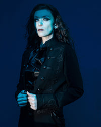 An elegant gothic military jacket with Victorian influences, featuring a cropped, tailored fit made from premium stretch ponte material for comfort and flexibility. Detailed with braided trim and embossed ouroboros buttons, the jacket’s high mandarin collar and open-front design add a commanding, timeless presence that pairs effortlessly with dresses or fitted tops.