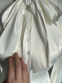 Ribbon details of the Angela Blouse in white on a white bust mannequin against a white wall.