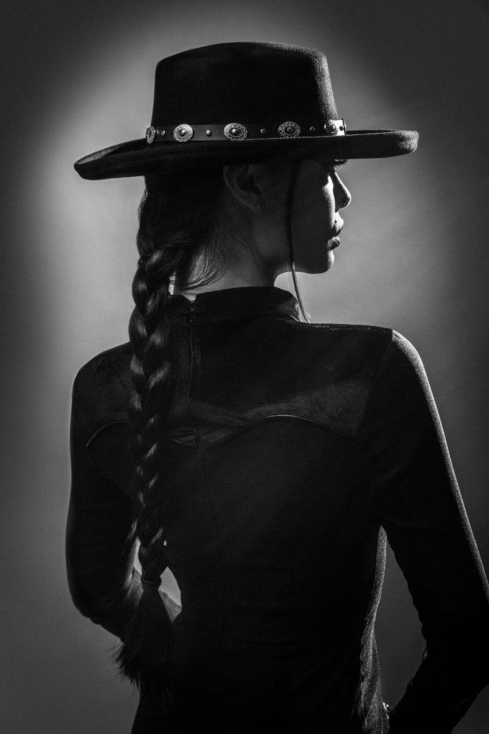 Traditional Western-style hat belt made from 100% vegan leather, featuring a black strap and classic silver concho design. One-size-fits-most accessory easily adds cowboy-inspired, gothic Western flair to any Katakomb hat, perfect for alternative fashion and dark Western outfits.