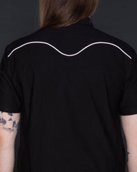 Classic black Johnny Western Shirt in premium soft Bengaline fabric, featuring a tailored fit, crisp collar, and unique western detailing. Accented with eye-catching white snap buttons, delicate minimalist piping, and a subtle rose pattern, this versatile shirt is a timeless addition to any wardrobe, suitable for casual wear, smart-casual ensembles, and layering with jackets or vests.