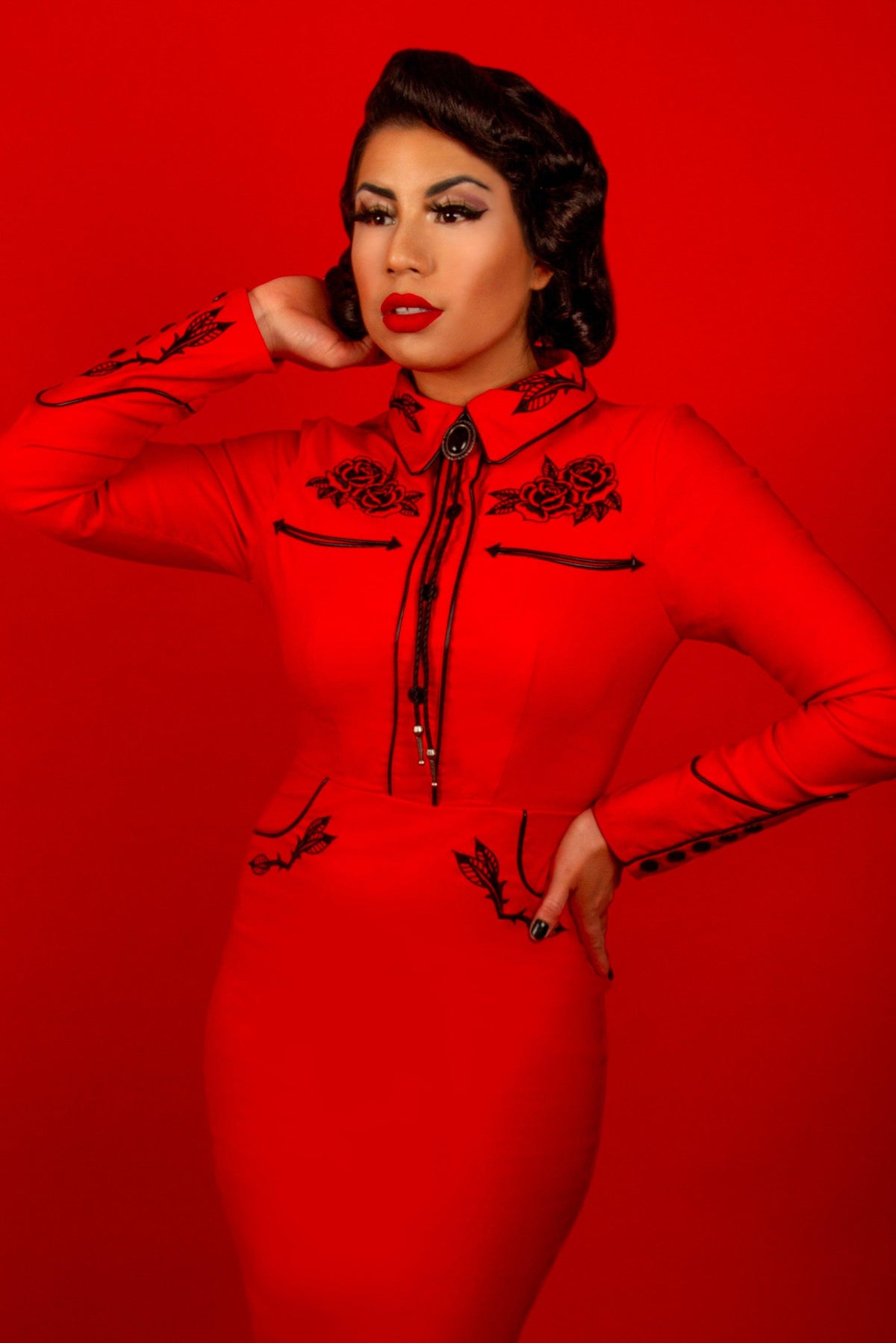 This embroidered red dress from Katakomb, known as the June Dress, captures a perfect balance of edgy western aesthetic and feminine grace. Crafted from stretch bengaline fabric for comfort and fit, it showcases detailed rose and thorn embroidery, faux snap cuffs, and seamless fixed front snaps, embodying the spirit of dark romantic vintage fashion.