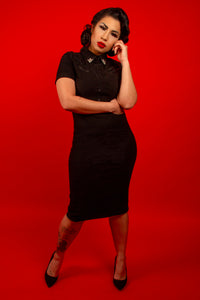 The Wanda Pencil Dress offers a striking blend of classic tailoring and modern detail, constructed from soft yet structured Bengaline fabric that smooths and flatters every curve. This iconic black pencil dress now includes updated snap closures for convenience, faux front snaps for visual appeal, and removable silver collar clips that add personality and Western-inspired style, all finished with refined pleather piping.