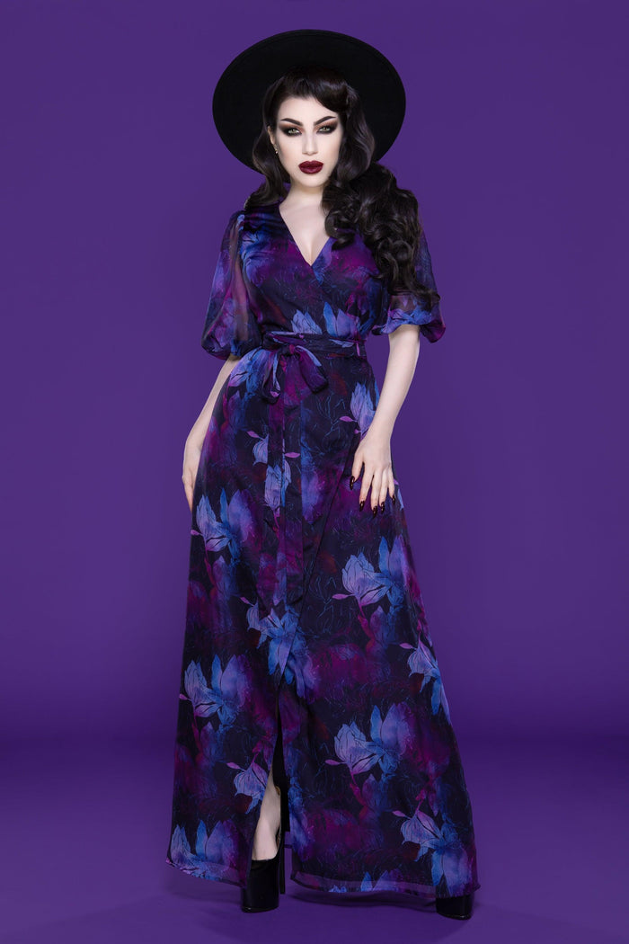 Elegant Winona maxi dress featuring a purple watercolor floral print, designed with a classic front wrap style and V-neckline, complete with flared bishop sleeves and a lightweight, floor-length chiffon skirt. This versatile dress includes hidden snaps for extra coverage and minimal stretch, offering a comfortable and flattering fit perfect for both casual beach days and sophisticated evening outings.