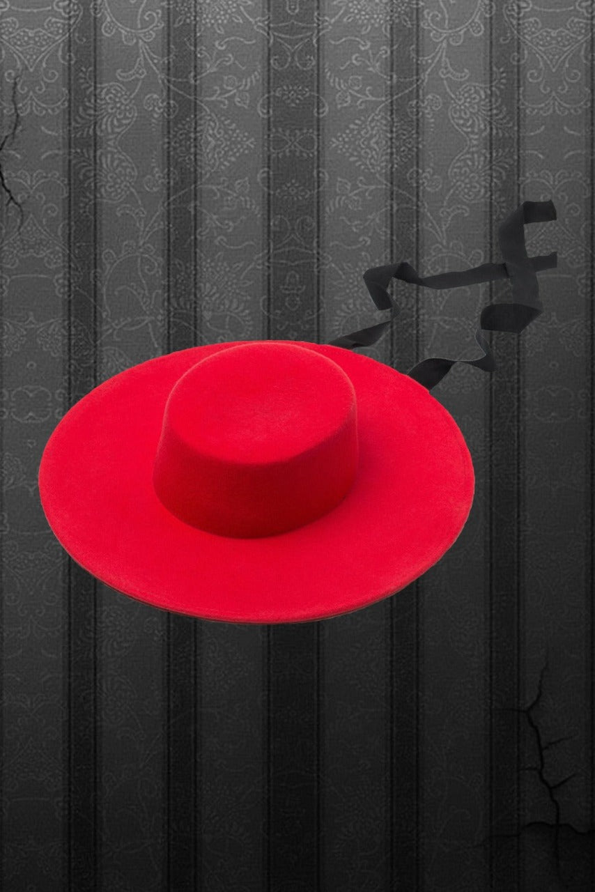 A red, wide brimmed wool hat with a black ribbon against a pin stripe background.