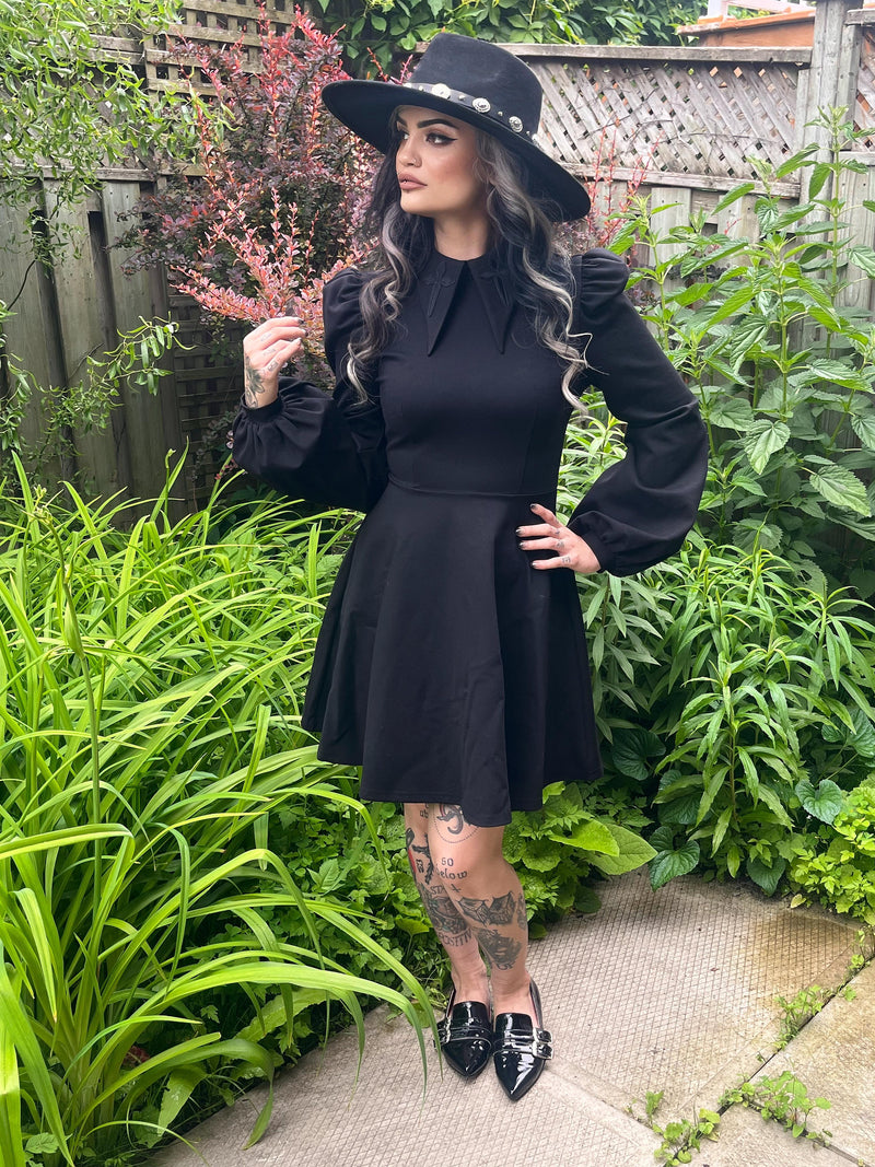 This black Baptism Dress is a lovely choice for formal celebrations, featuring a statement pointed collar with delicate cross embroidery that can be black for classic elegance or red for a pop of color. The dramatic puffed shoulders and flowing bishop sleeves give the dress a sense of sophistication and charm, while the soft, stretchy ponte fabric ensures you stay comfortable, warm, and ready to enjoy every moment of your day.