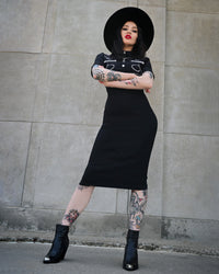 Designed for bold elegance, the black Barbara Dress hugs the figure with a perfect balance of stretch and support, thanks to its high-quality Bengaline construction. The piece is adorned with distinctive barbed wire embroidery, adding a rebellious twist to the classic western aesthetic. Refined piped yokes shape the shoulders and bust, while decorative snaps on the front and a hidden zipper in the back complete the sophisticated yet daring silhouette.