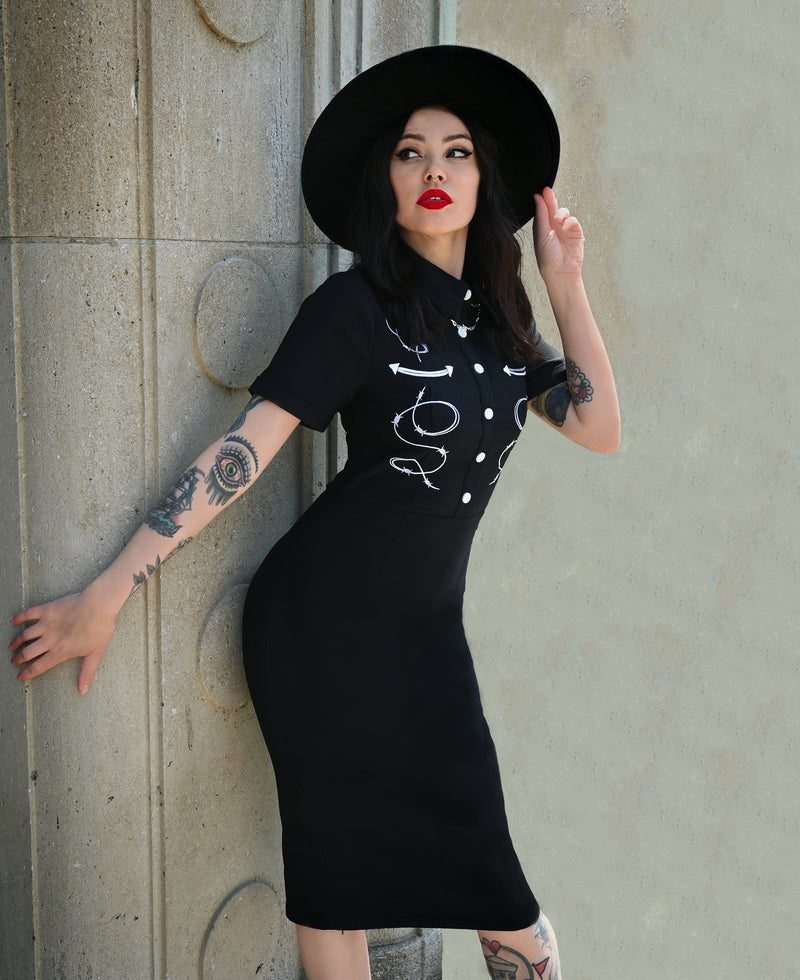 The black Barbara Dress embodies modern western allure with its form-fitting Bengaline fabric and striking embroidered barbed wire motif. Its tailored design includes carefully piped yoke detailing for contour and style, complemented by a row of front snap buttons that enhance its vintage charm. Finished with a concealed zipper in the back, this curve-hugging dress delivers both comfort and structure—ideal for statement looks that merge classic femininity with a bold, barbed-edge aesthetic.