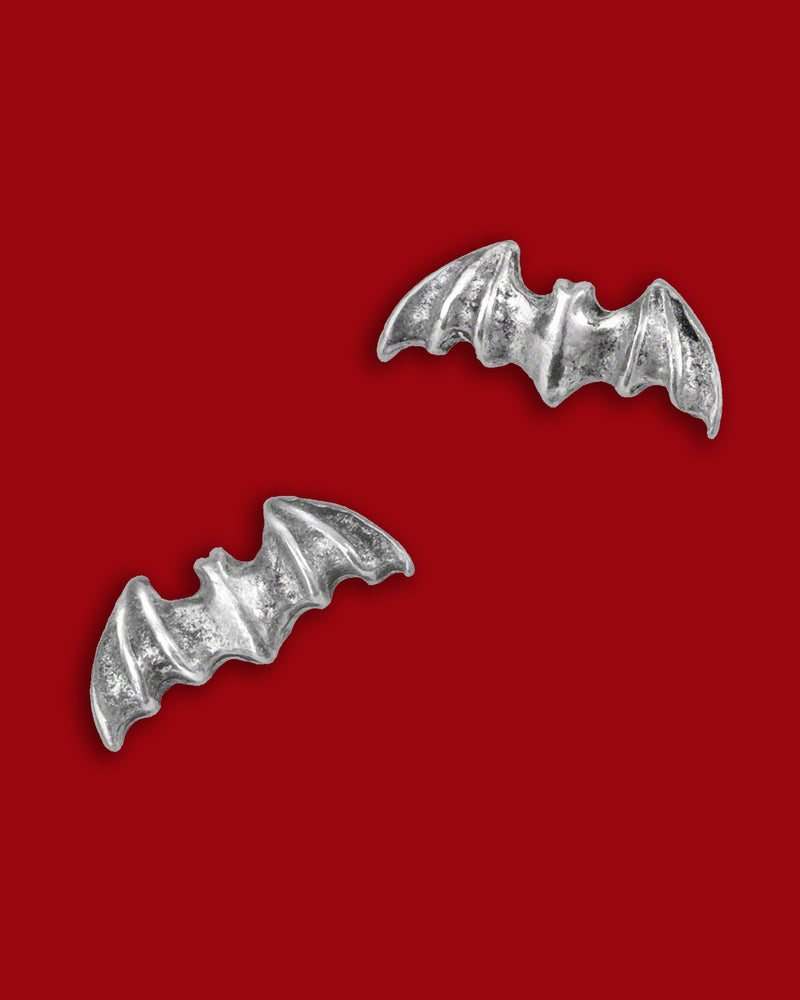 A pair of finely crafted bat‑wing stud earrings in English pewter with surgical steel posts, designed for subtle gothic elegance—perfect for everyday wear or adding nocturnal charm to any outfit. With an approximate width of 0.51″ and a height of 0.20″, these earrings offer a sleek silhouette that balances dark symbolism and minimalist design. Hypoallergenic and compliant with jewelry safety standards, they bring a discreet yet edgy accent to playlists of gothic accessories and modern wardrobes alike.