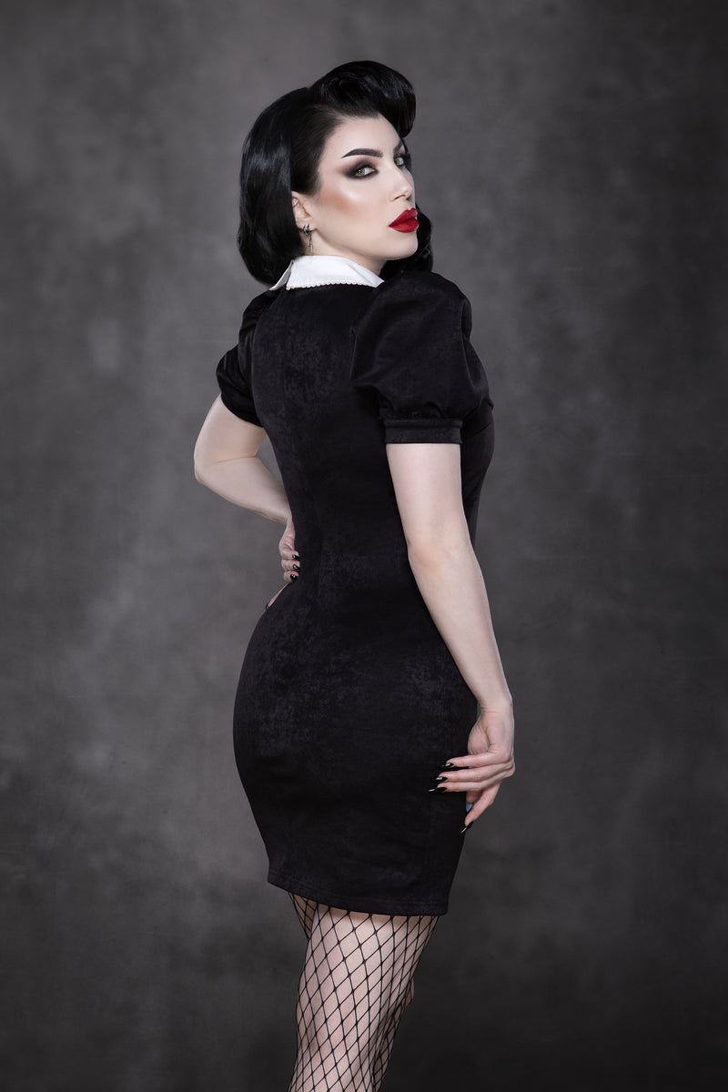 The Bellatrix Dress combines a short, tight black suede silhouette with voluminous puff sleeves and an oversized white collar adorned with intricate black sword embroidery, offering a vintage-inspired gothic alternative dress that balances edgy design, retro charm, and modern fashion appeal for standout occasions.
