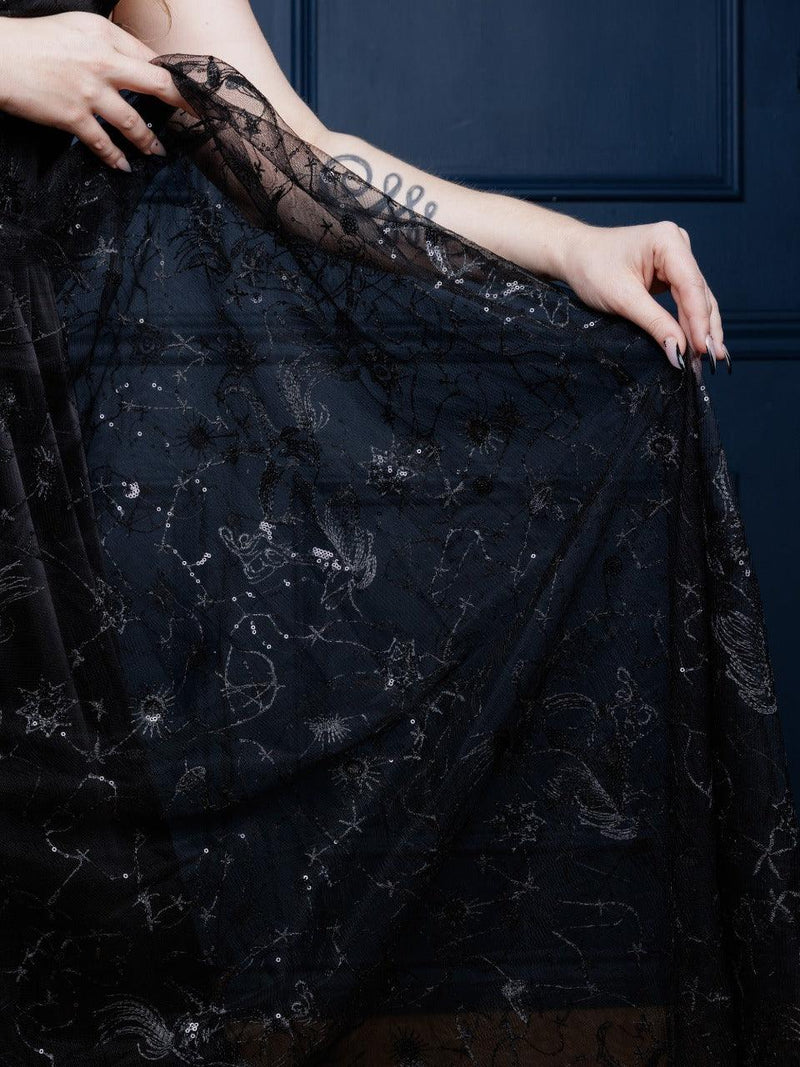 Sophisticated Celestial Dress in black or white embroidered chiffon, featuring a subtle starry constellation print, sparkly shimmer, low-cut neckline, and cross-strap accents. Perfect for special occasions, evening celebrations, or formal gatherings, this maxi dress combines modern chic with timeless elegance.