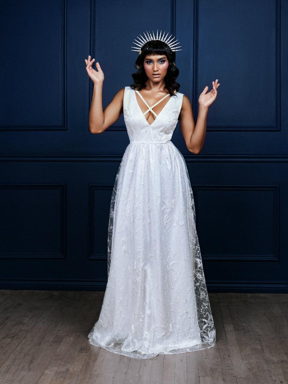 Celestial Dress in embroidered chiffon with a subtle constellation pattern, available in black and white. This elegant maxi dress features sparkly fabric, a low-cut neckline, and chic cross-strap detailing, perfect for special events, evening parties, or nights out, offering timeless sophistication and modern celestial style.