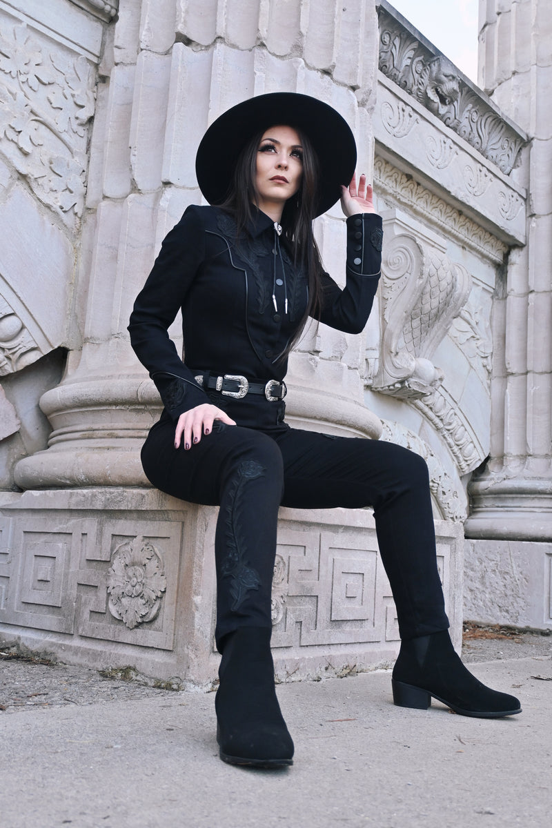 Tailored high-waisted black Dallas Pants crafted from stretch denim, offering a fitted silhouette with all-day comfort. Accented with subtle tonal black rose and thorn embroidery down the legs, functional belt loops, and a back zipper for a sleek, dark romantic finish.