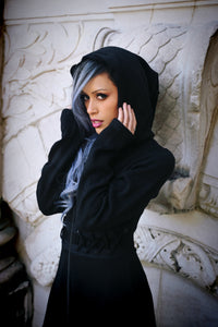 The Demille Cardigan by Poizen Industries in deep black is crafted from soft, stretchable polyacrylic, featuring a zip-up front, corset-style lacing details, oversized hood, high-low hemline, and thumbholes, combining comfort, edgy style, and versatile layering for alternative fashion outfits.