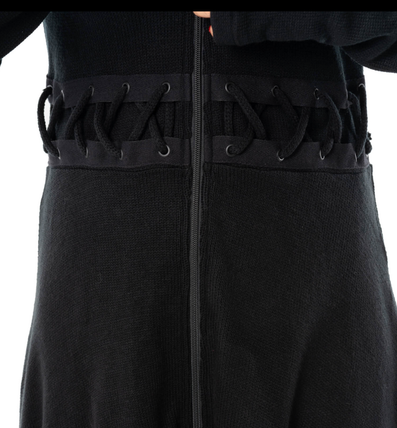 A moody, full-length black Demille Cardigan made from soft polyacrylic with structured edges, front and back corset lacing, oversized hood, zip closure, high-low hem, and thumbholes, perfect for gothic fashion enthusiasts seeking versatile layering pieces or statement outerwear.