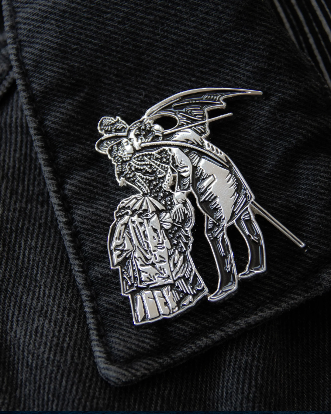Silver metal and black enamel enamel brooch inspired by Gustave Doré and Max Ernst, showing a gothic, surreal scene of a woman and a winged man. Size 2 x 1.71 inches with secure dual clasps, ideal for black denim jackets, bags, or layered with other gothic pins for alternative style collections.