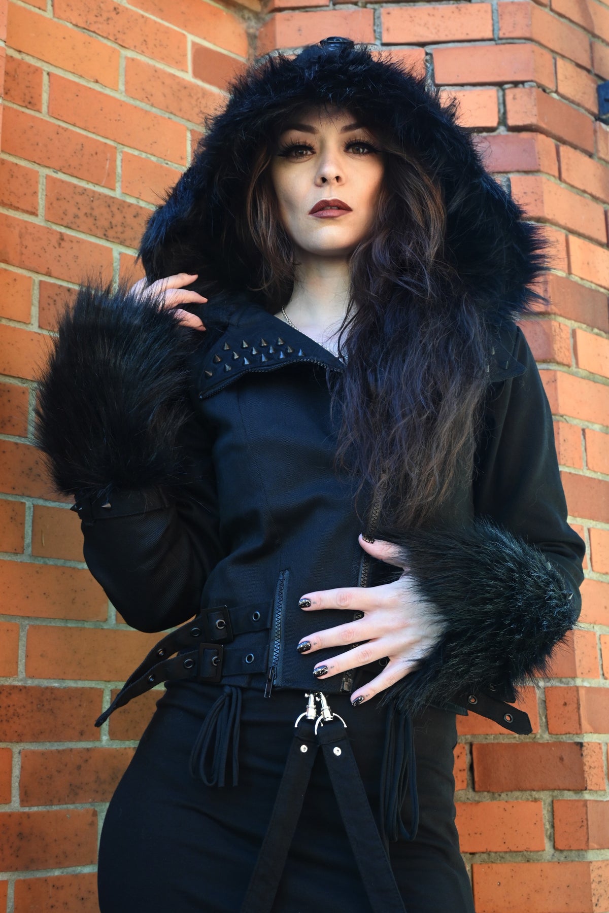 Stylish Effia Jacket by Heartless featuring durable 100% cotton outer, plush polyester faux fur hood and cuffs, matte black stud embellishments, asymmetrical front zip, and contoured fit with adjustable side straps, designed as a modern, statement black jacket for winter.