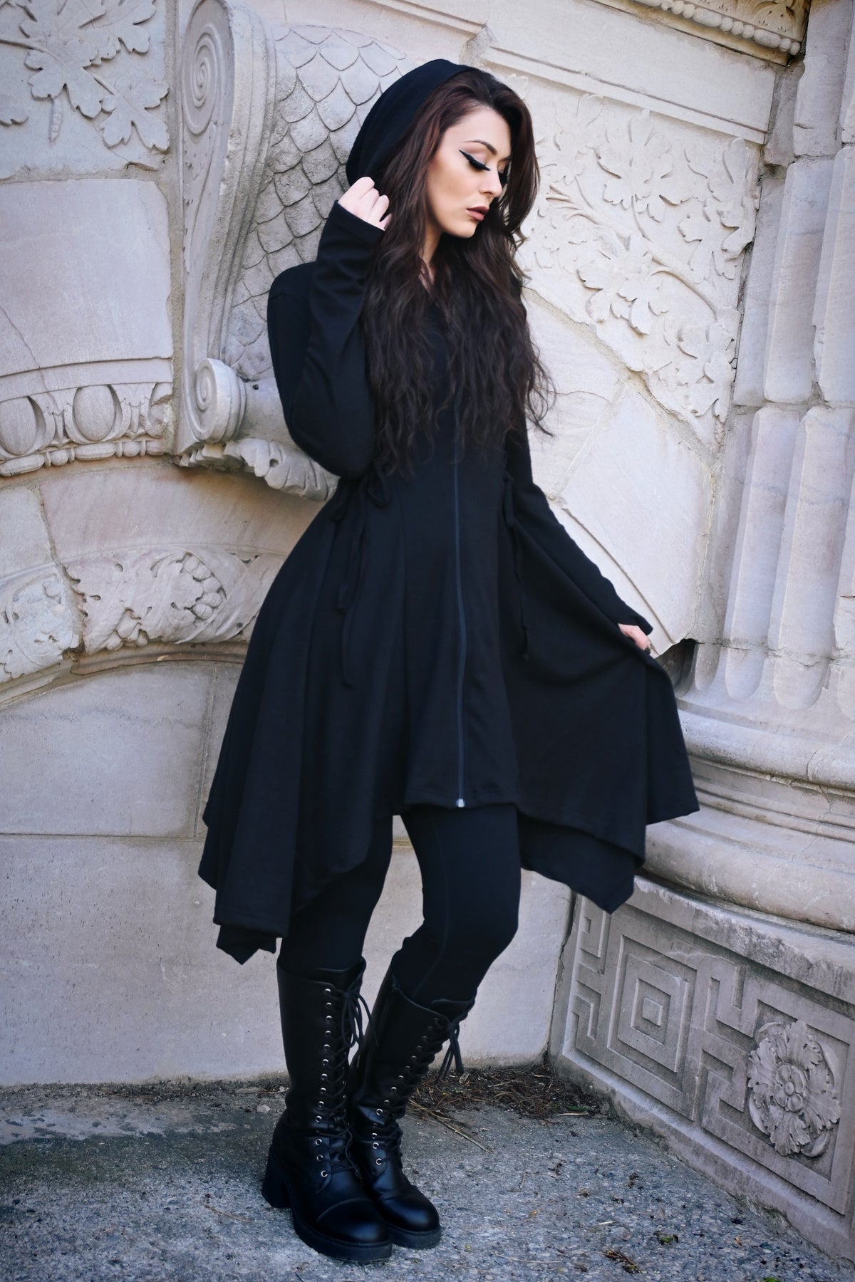 A lightweight black Emerson Cardigan by Innocent Lifestyle featuring a soft drape, mid-length design, corset-style side and back lacing, a handkerchief hem, and an elongated hood for a flattering gothic-inspired silhouette.