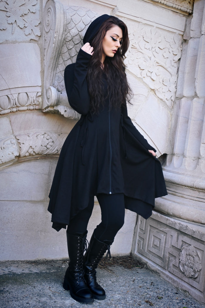 A lightweight black Emerson Cardigan by Innocent Lifestyle featuring a soft drape, mid-length design, corset-style side and back lacing, a handkerchief hem, and an elongated hood for a flattering gothic-inspired silhouette.