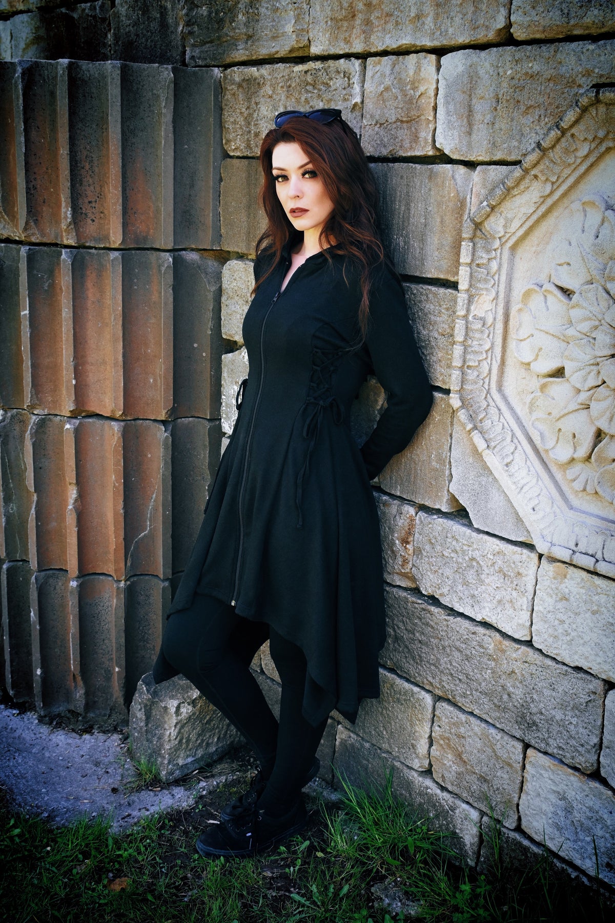 Mid-length black Emerson Cardigan with elongated hood by Innocent Lifestyle, crafted from 100% polyester, offering a dramatic gothic edge with corset-style lacing details, handkerchief hem, and a flowing drape perfect for everyday or evening wear.