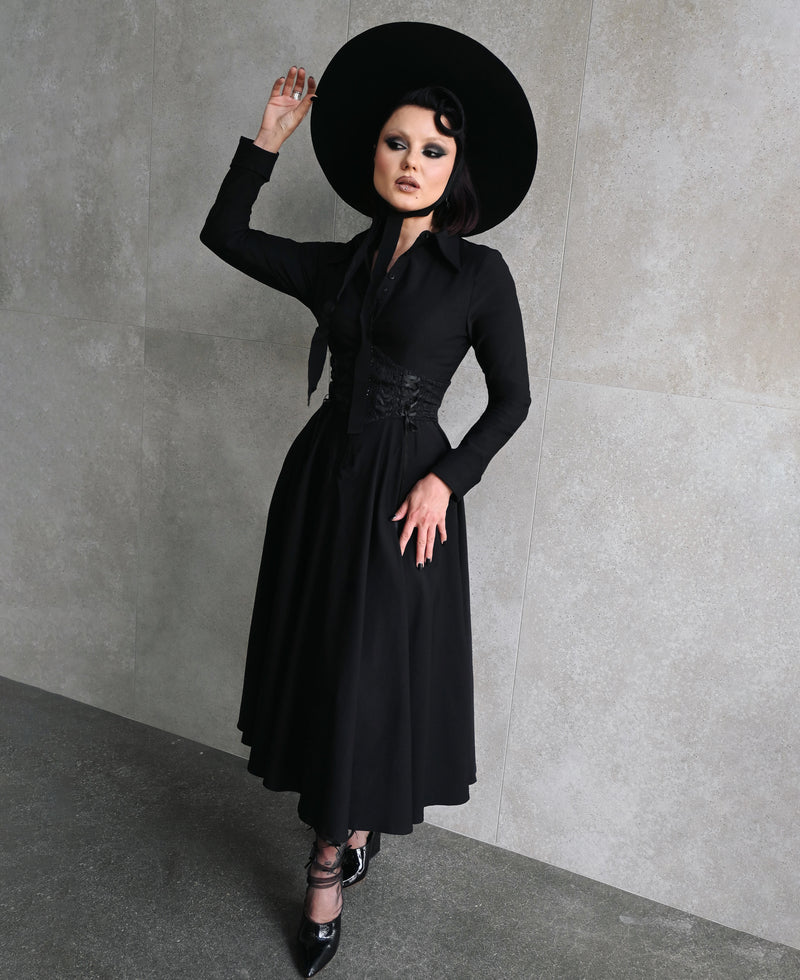 Designed for versatility, the Homemaker Swing Dress in black features a flattering midi-length cut and long sleeves, making it suitable for various occasions. The hidden front button placket and functional side pockets combine style with functionality. The high-stretch Bengaline fabric ensures a comfortable fit, while the flared skirt adds a touch of elegance to the overall design.