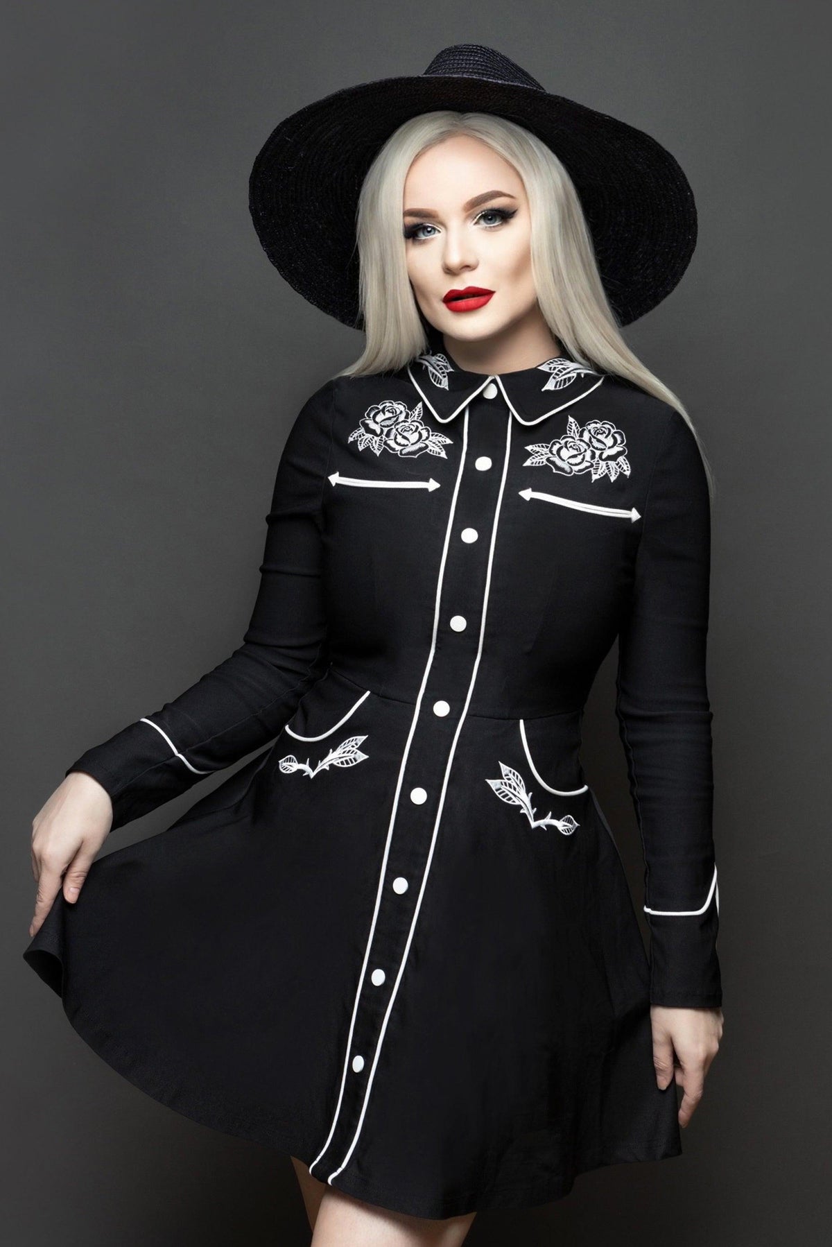 Flattering skater-style dress for women with embroidered rose and thorn detailing across the collar, cuffs, bust, and hips, accented with crisp white piping, long piped sleeves with faux snap cuffs, a playful A-line skirt with built-in pockets, offering a stylish and functional dress suitable for both casual and semi-formal occasions.