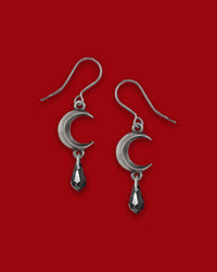 A pair of elegant pewter moon-shaped earrings fashioned with a jet-black Austrian crystal drop, symbolizing tidal magic and lunar mystery, crafted from fine English pewter and surgical-steel ear-wires—lead, cadmium and nickel compliant.