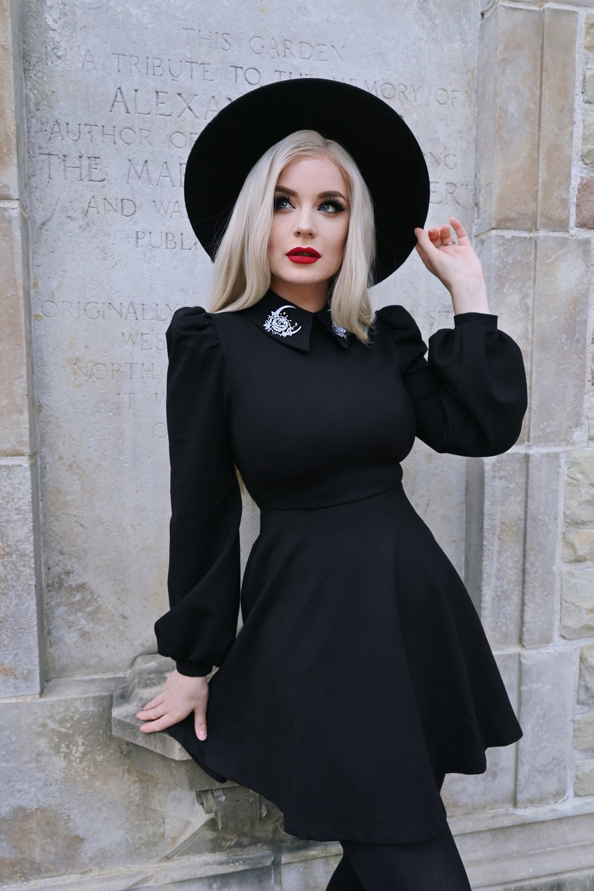 A black Moon Flower Dress featuring a wide collar adorned with intricate white flower and moon embroidery, designed to capture celestial elegance with puff shoulders and bishop sleeves made from thick, high-stretch ponte fabric that offers both comfort and structure for cooler seasons.