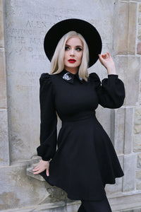 A black Moon Flower Dress featuring a wide collar adorned with intricate white flower and moon embroidery, designed to capture celestial elegance with puff shoulders and bishop sleeves made from thick, high-stretch ponte fabric that offers both comfort and structure for cooler seasons.