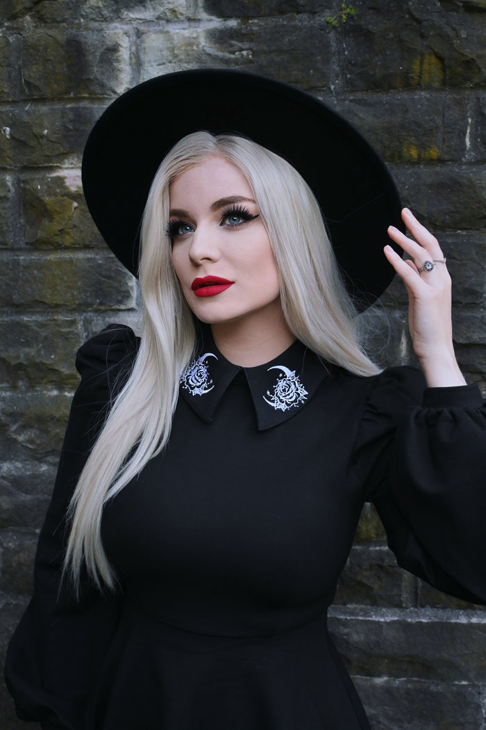 Elegant black dress called the Moon Flower Dress, crafted from durable ponte fabric with a soft stretch fit, showcasing a statement collar decorated with delicate moon and floral embroidery, puffed shoulders, and flowing bishop sleeves that add a touch of gothic romance and sophistication.