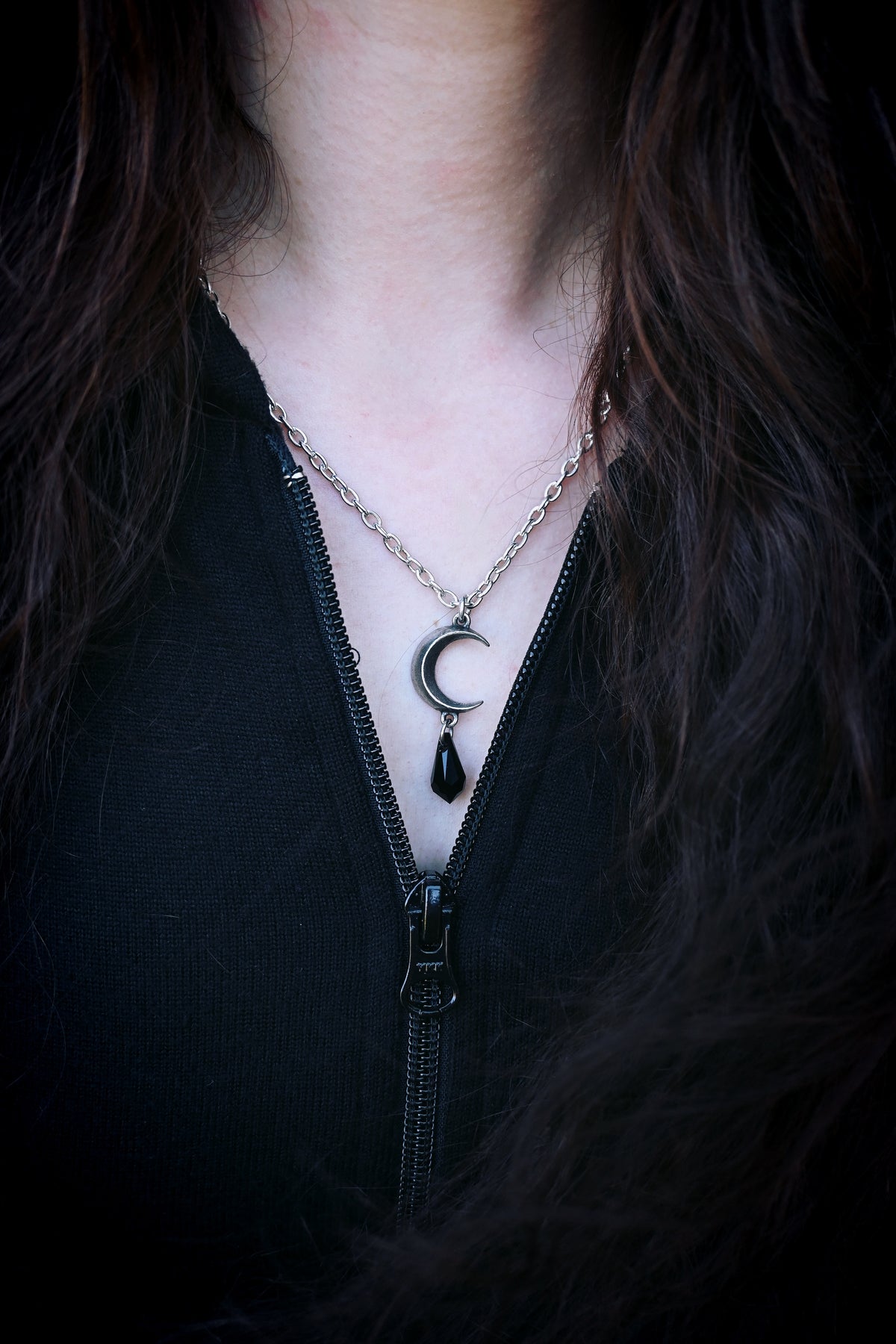 This pendant offers a dramatic blend of celestial symbolism and refined craftsmanship—crafted in English pewter, the moon-shaped top supports a faceted jet-black crystal drop that catches light and attention. Designed with adjustable chain length and night-inspired narrative (“the Goddesses' tears cleave the night asunder”), the piece serves as both jewellery and storytelling accessory.