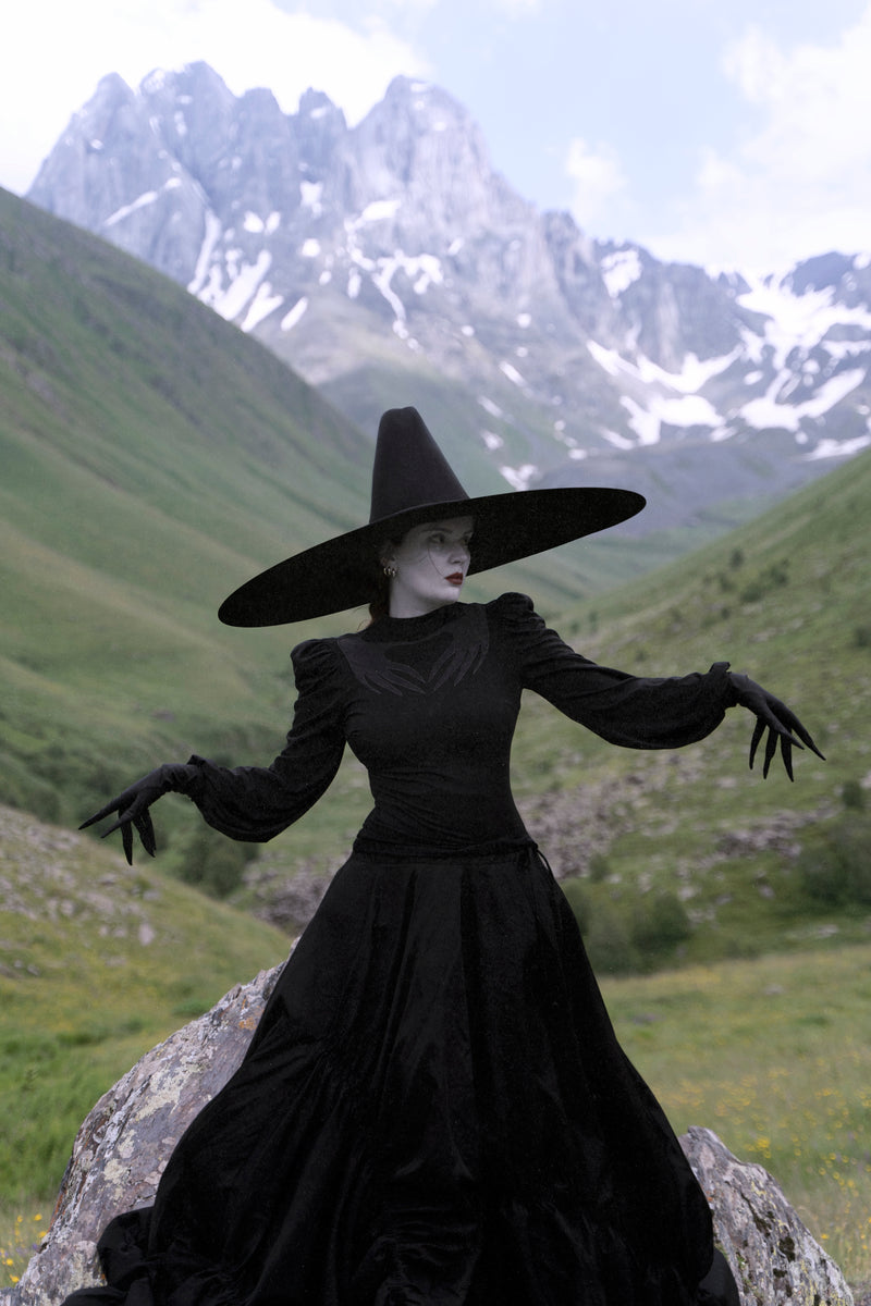 Black Phantom Blouse featuring puffed shoulders, long gathered sleeves, and a sheer mesh panel with Naya’s hand design across the chest, made from high-stretch polyester for comfort and a dramatic, gothic-inspired look.